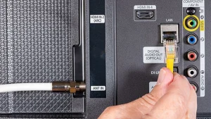Waarom IPTV blokkeert in Nederland: blokkades, storingen en accountoorzaken 3 Een hand sluit een gele ethernetkabel aan op de LAN-poort van een televisie.
