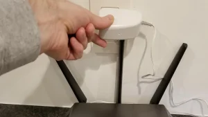 Waarom IPTV blokkeert in Nederland: blokkades, storingen en accountoorzaken 7 Een hand bij de voedingsadapter naast een wifi-router om de stroomtoevoer te onderbreken.